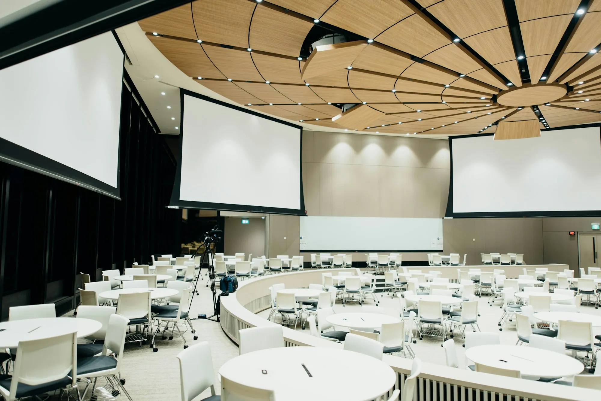 Salle de conférence avec tables rondes et écrans, installée pour un séminaire