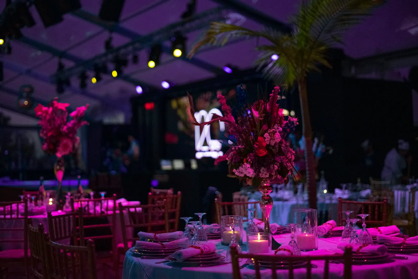 Soirée d’entreprise décorée : compositions florales roses, bougies et lumière violette